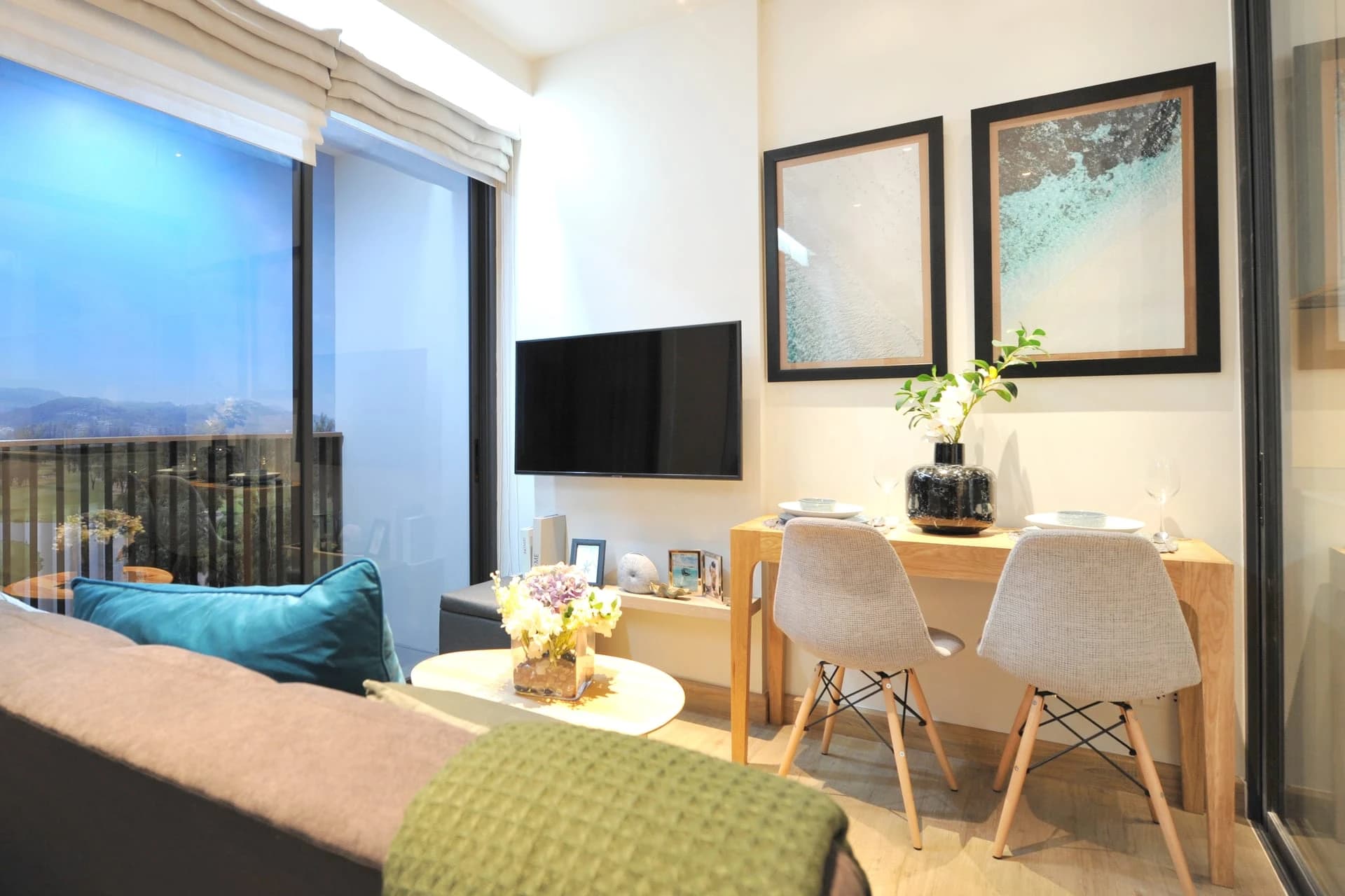 Show unit, type 1A: sofa, small dining table and TV beside the full-height window